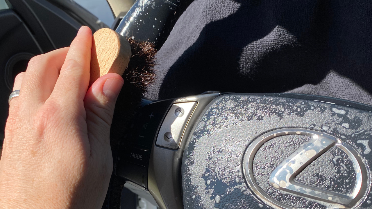 Lexus steering wheel being cleaned by a leather brush